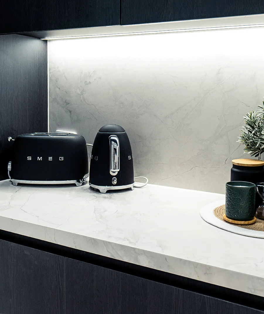 Pale stone benchtop and splashback set against dark kitchen cabinetry