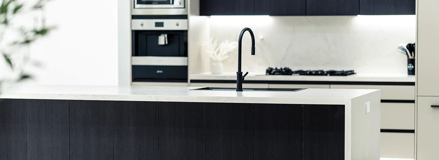 Black and white kitchen with a waterfall stone island and black tapware