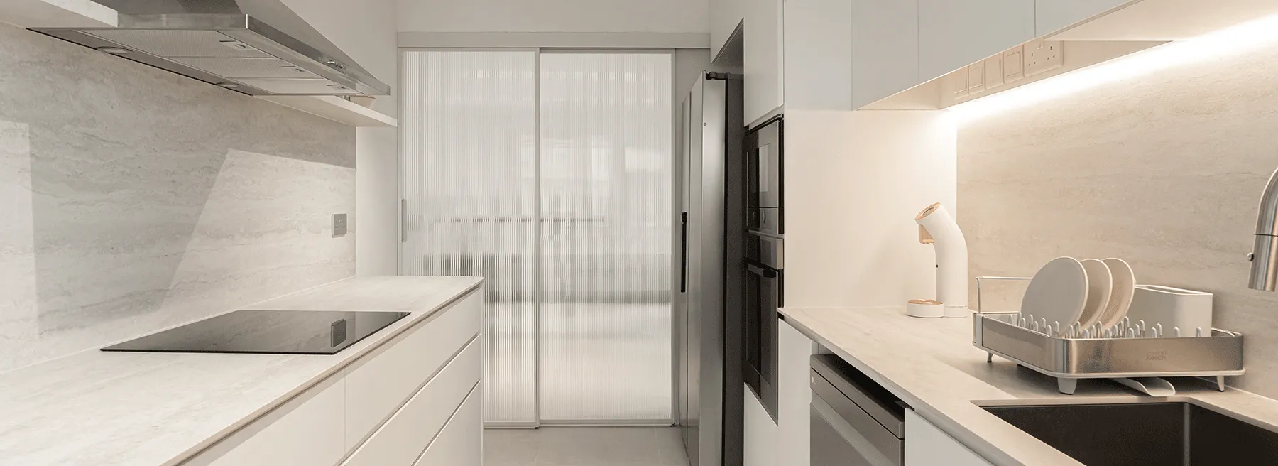 Bright galley kitchen with pale stone benchtops and splashbacks