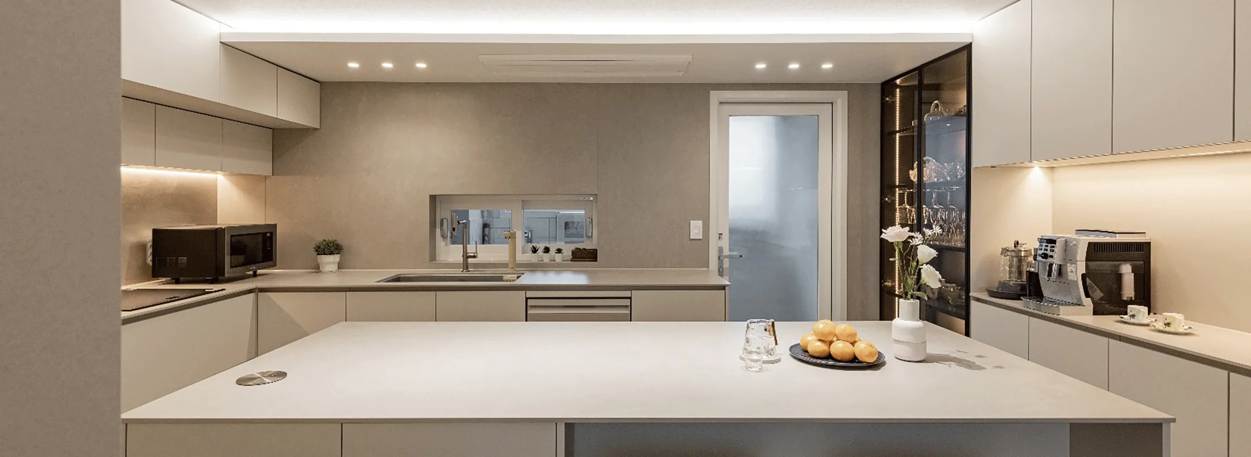 Contemporary neutral kitchen with a broad pale stone island