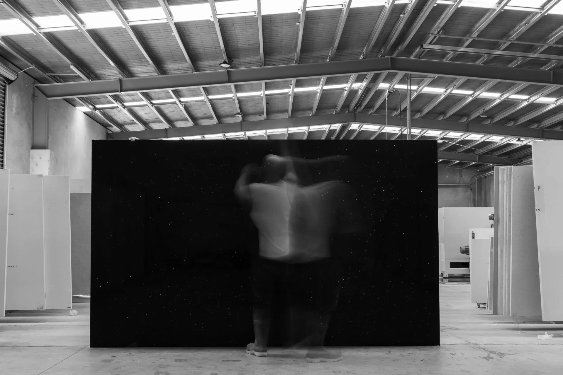 Lucino team handling a large dark stone slab in the Christchurch workshop