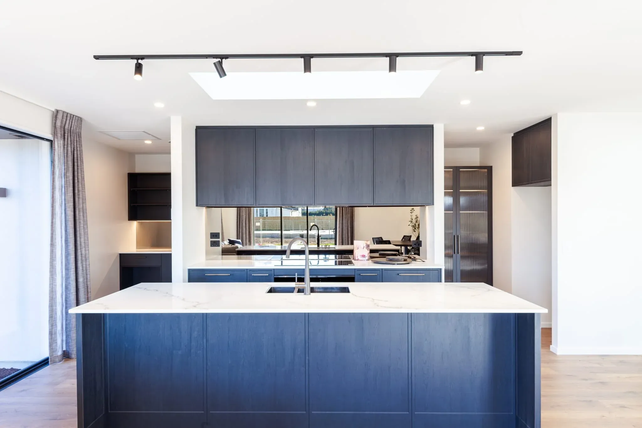 Trendsetter Homes show home kitchen with dark cabinetry and a Hellenic stone island